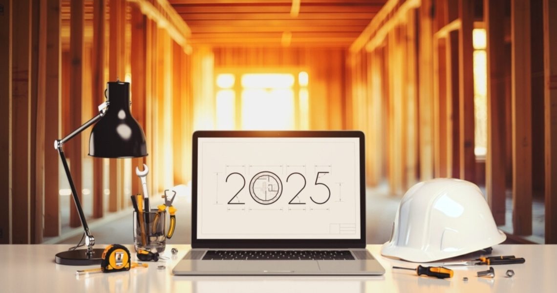 A laptop screen beside a construction helmet saying '2025'