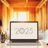 A laptop screen beside a construction helmet saying '2025'