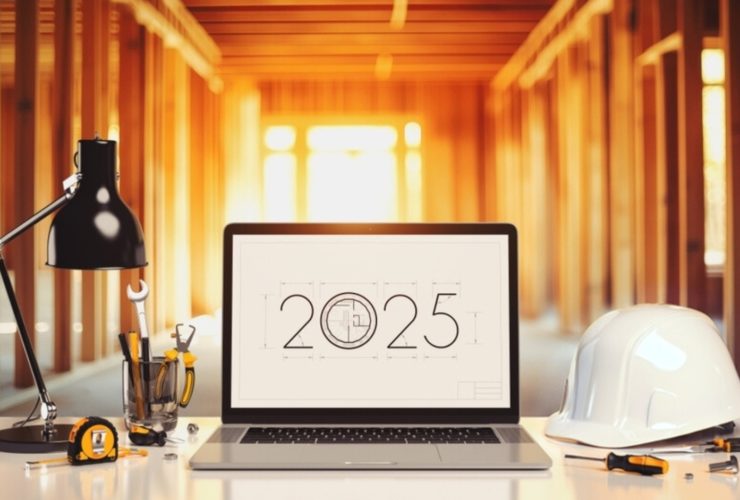 A laptop screen beside a construction helmet saying '2025'