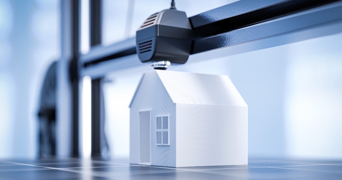 A small white house model being 3D printed