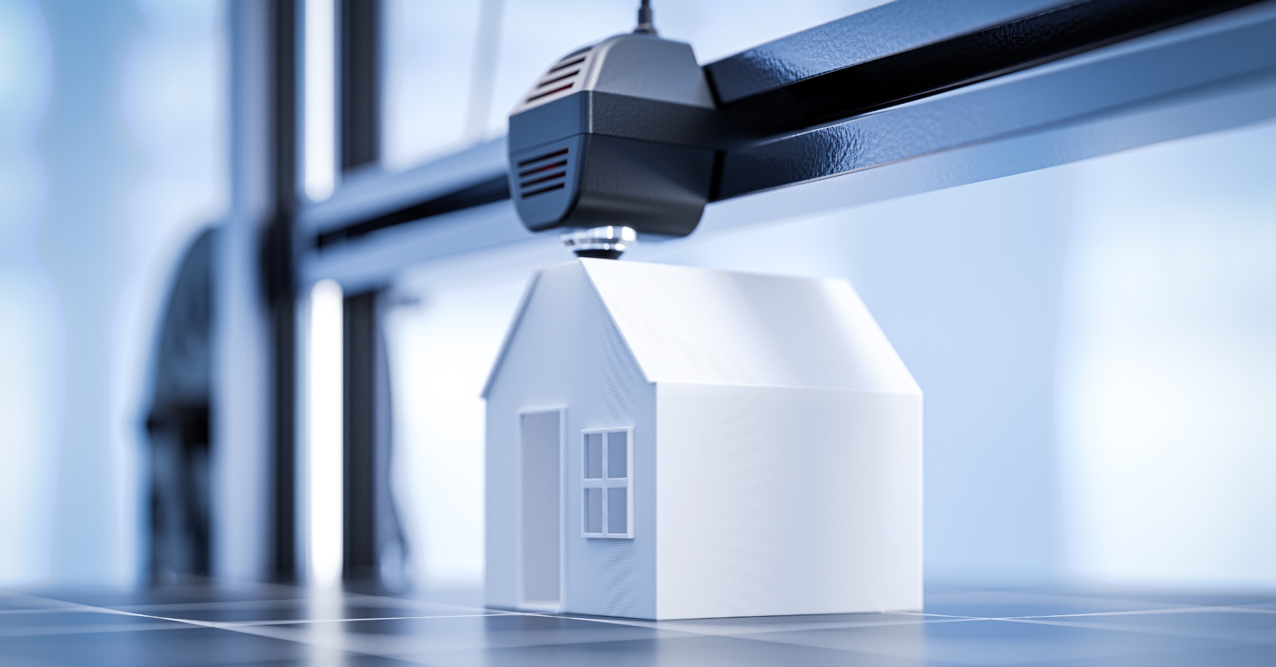 A small white house model being 3D printed