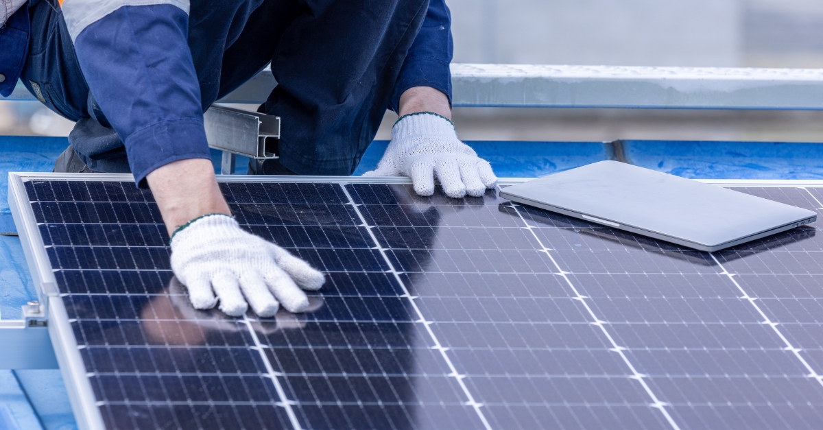 A construction worker fitting a solar panel