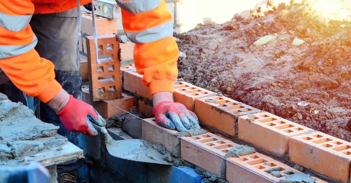 A bricklayer begins laying bricks