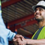 Two construction workers shake hands building a career