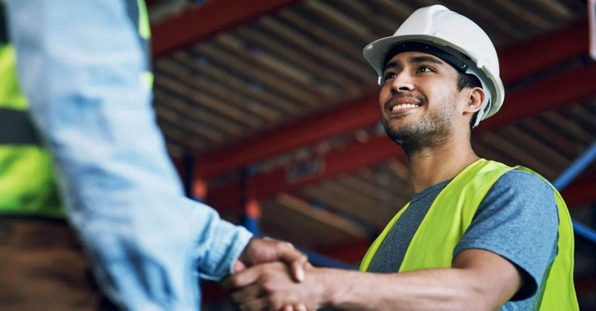 Two construction workers shake hands building a career