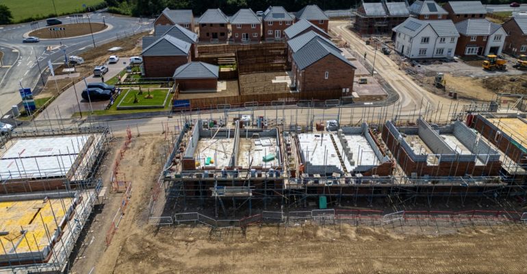 Construction industry growth New housing development under construction in the UK with brick houses, scaffolding and roads forming a growing estate