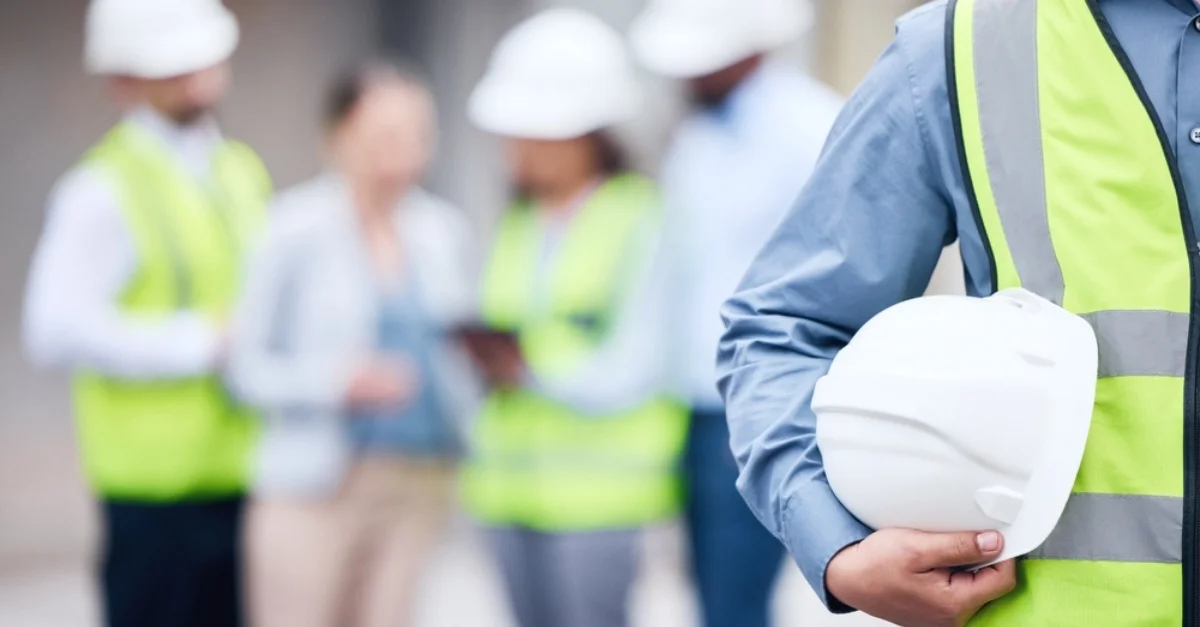 A group of construction workers in white hard hats and hi vis jackets