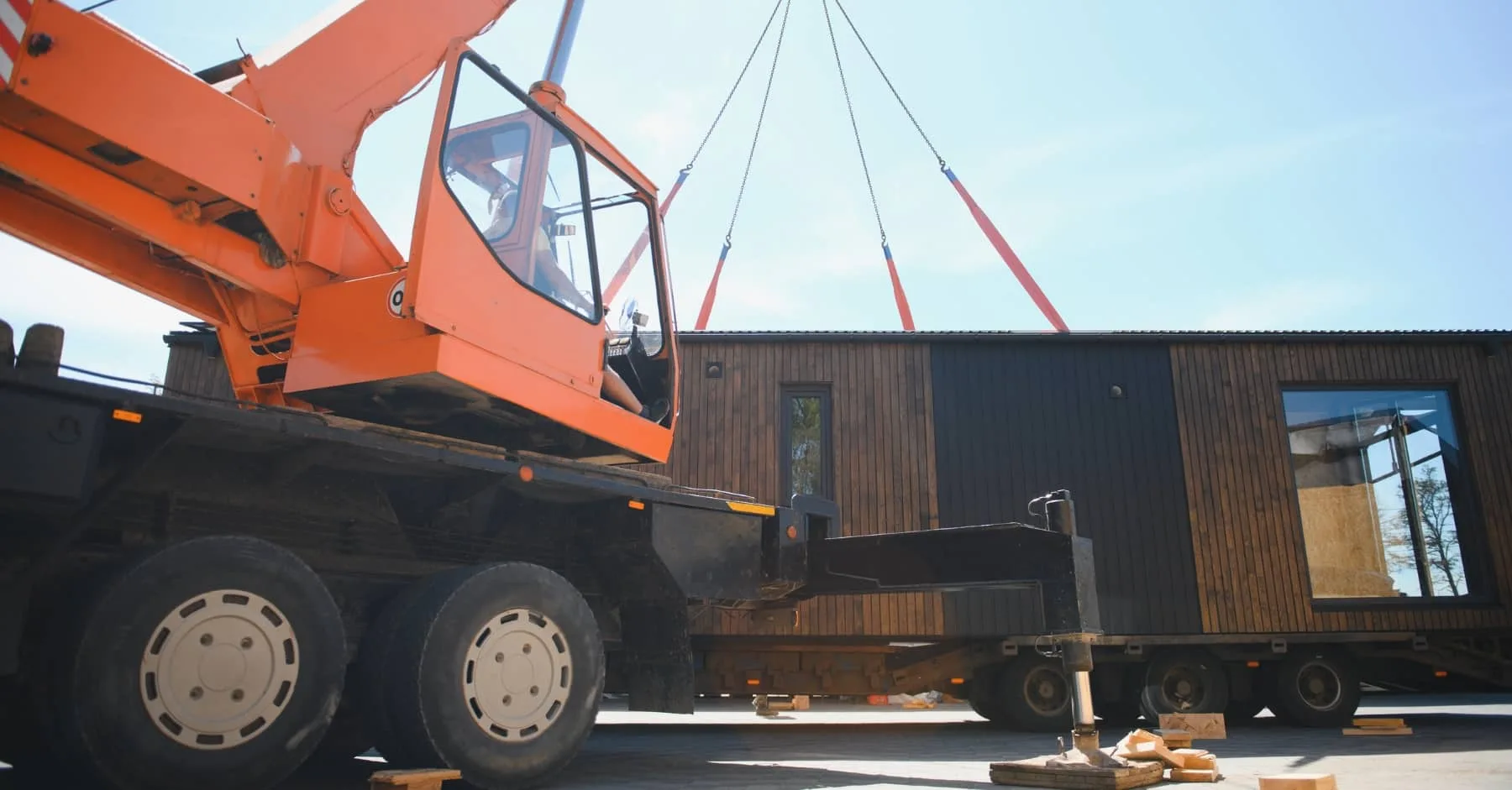 Large crane lifting a prefabricated modular building into position on a building site.