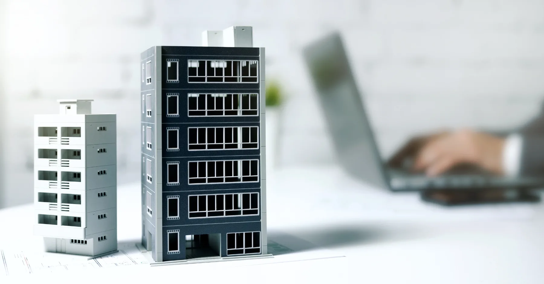 An image of two model towerblocks next to a man working on his laptop