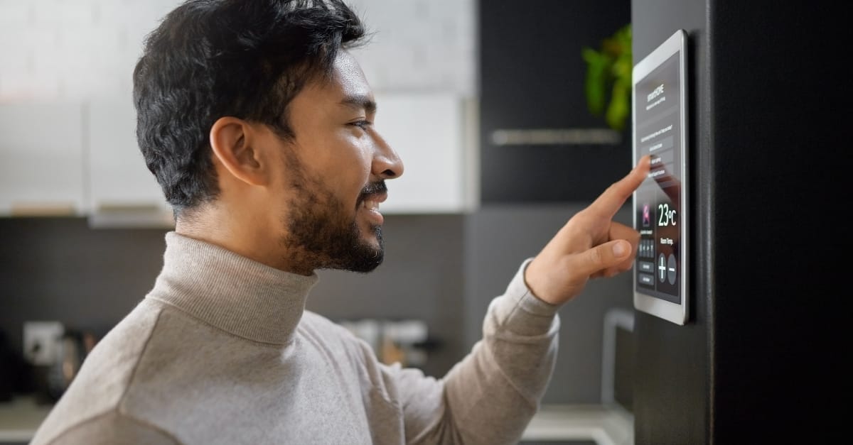 A man adjusts his SMART home thermostat