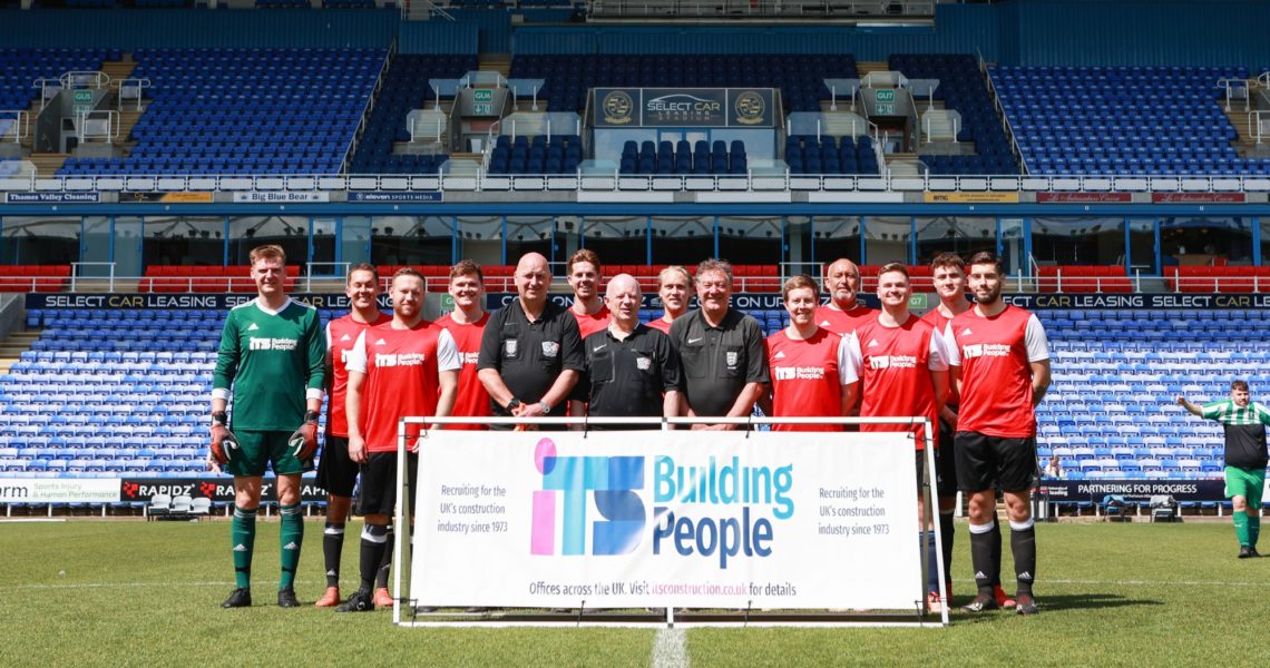 Footballers holding an ITS Building People banner in a football stadium