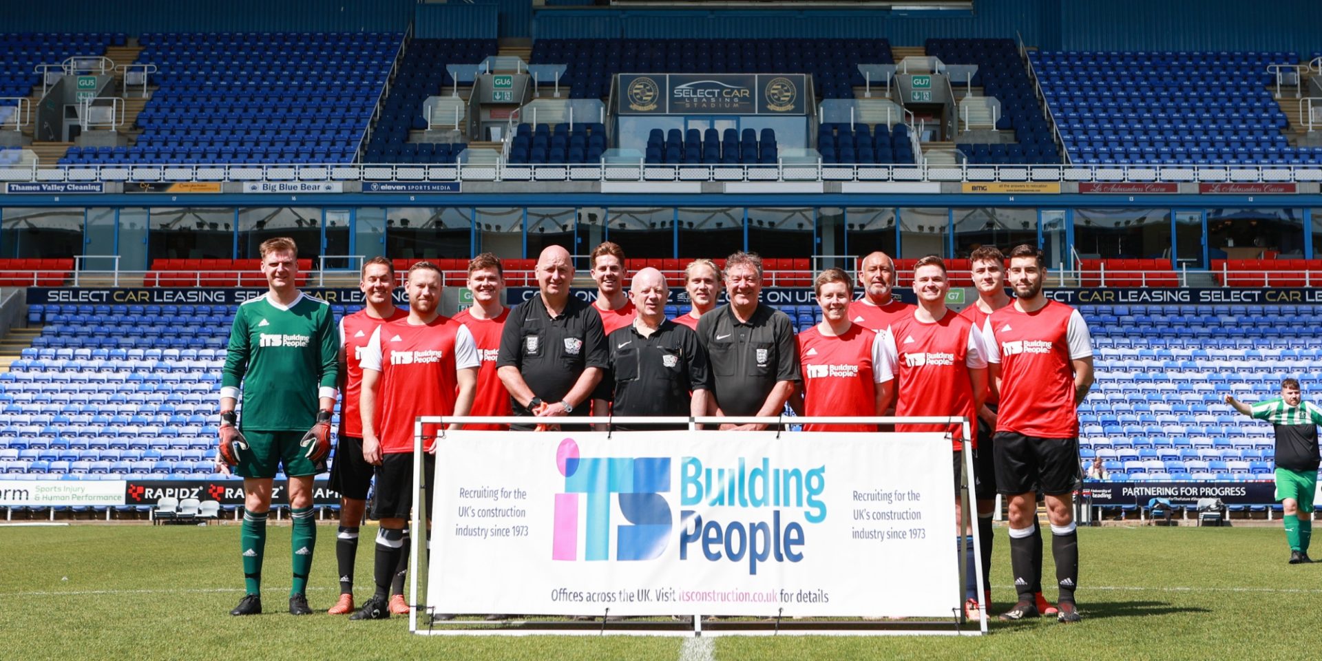 Footballers holding an ITS Building People banner in a football stadium