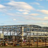 UK construction sector – Large steel frame commercial building under construction on an open development site.