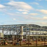 UK construction sector – Large steel frame commercial building under construction on an open development site.