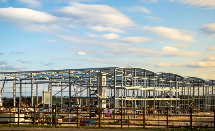 UK construction sector – Large steel frame commercial building under construction on an open development site.