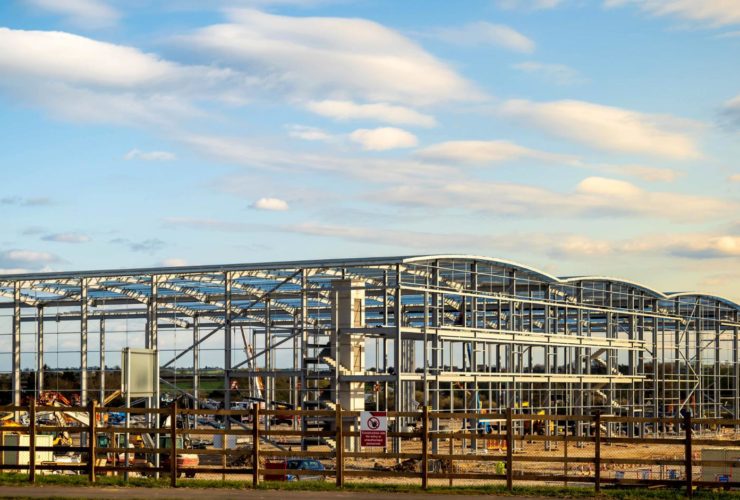 UK construction sector – Large steel frame commercial building under construction on an open development site.