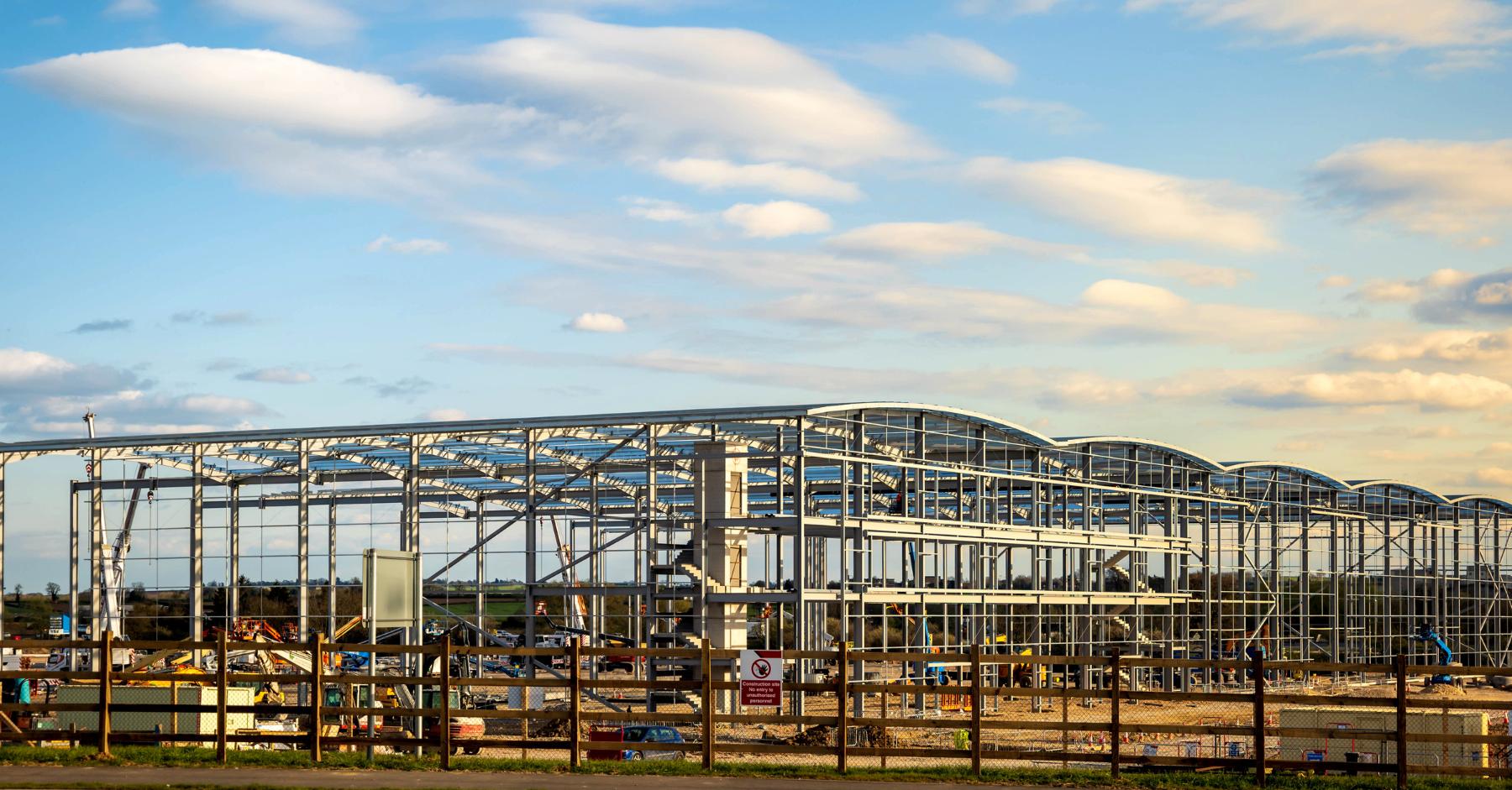 UK construction sector – Large steel frame commercial building under construction on an open development site.