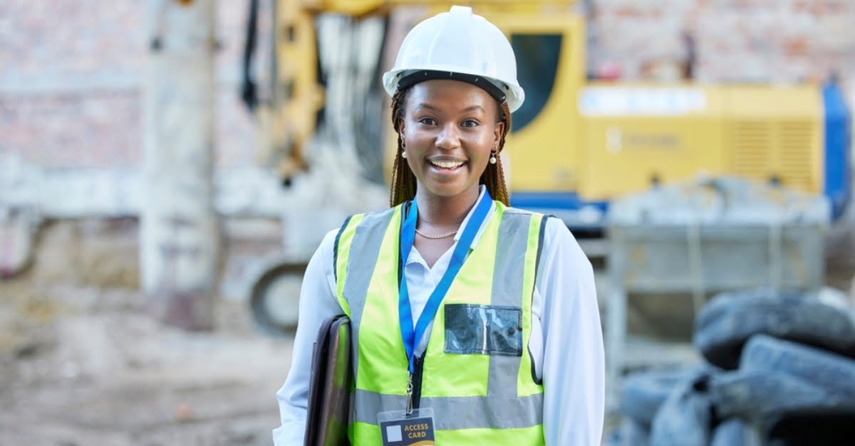 A young woman in a hard hat and hi vis jacket on a construction site