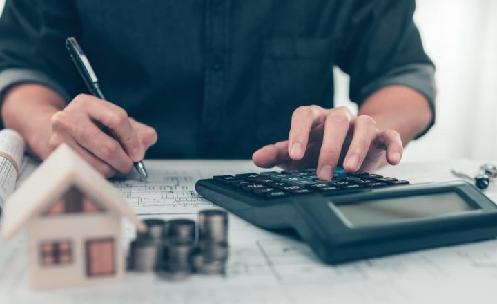 Architect reviewing blueprints and calculating figures to manage project finance effectively.