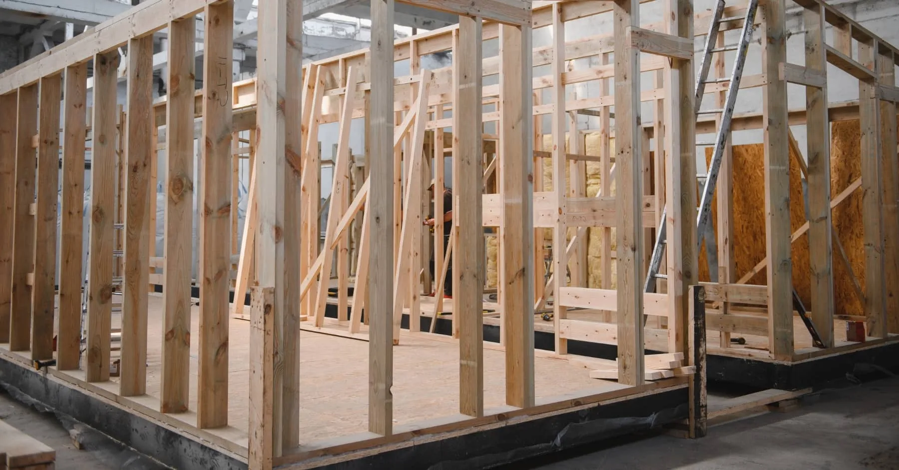 Wooden frame of a prefabricated modular building under construction inside a factory.
